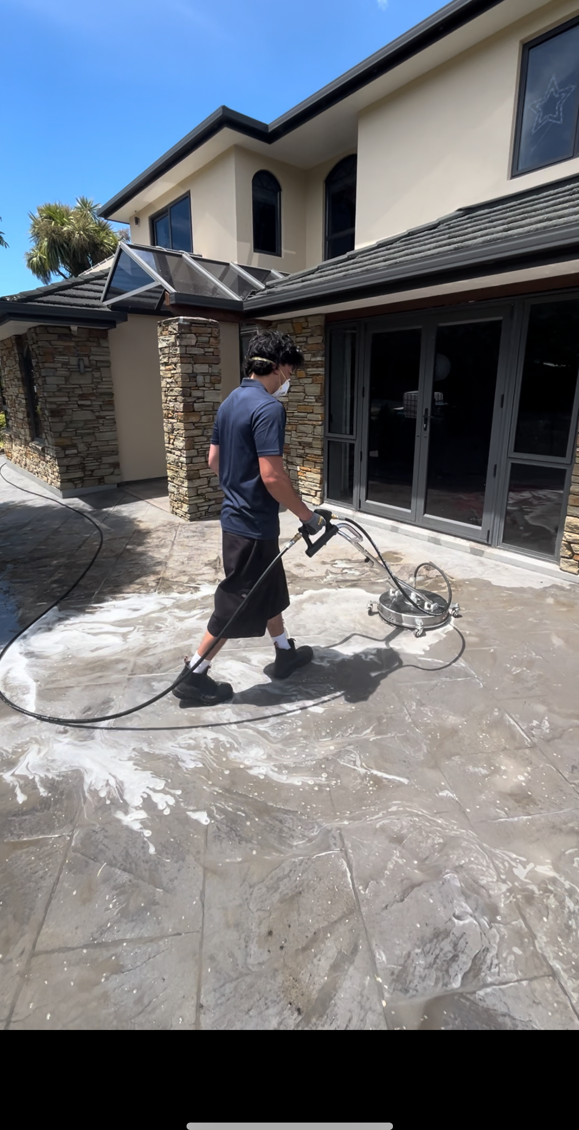 A TrueShine technician cleaning a tiled patio with a rotary surface cleaner in Wellington