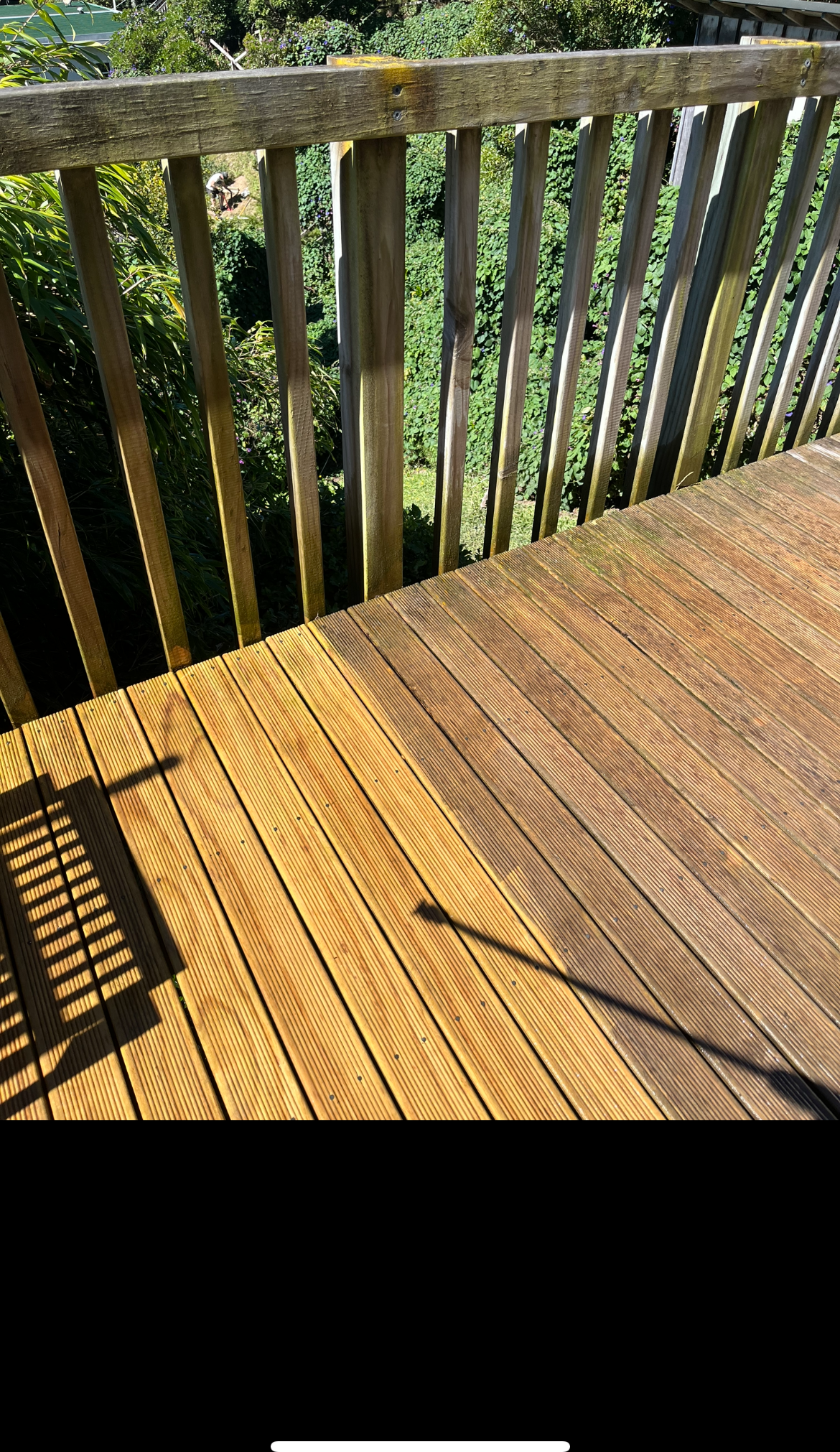 A timber deck being cleaned in Wellington — freshly washed boards on one side, grimy on the other