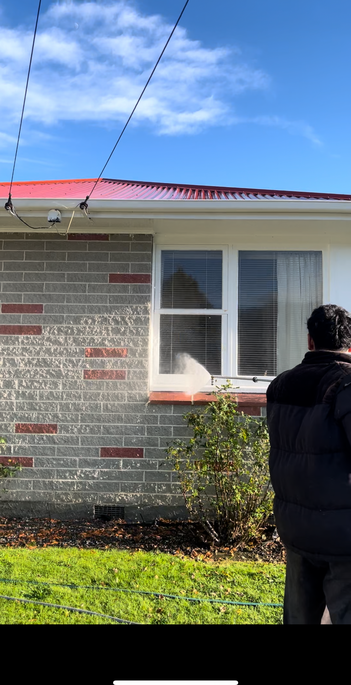A TrueShine technician cleaning the windows of a Wellington home from the garden